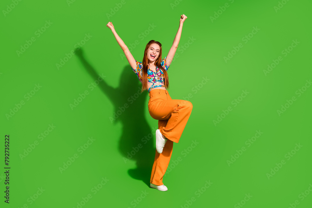 Photo portrait of attractive young woman raise fists winning dressed stylish retro clothes isolated on green color background Photo portrait of attractive young woman raise fists winning dressed stylish retro clothes isolated on green color background