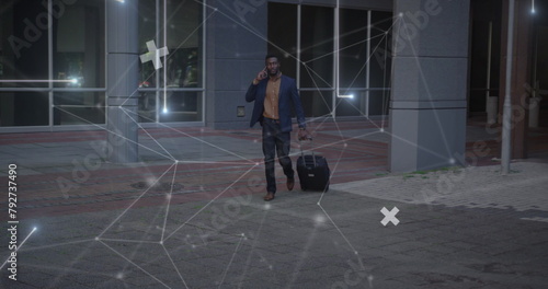 Image of network of connections over african amercian businessman with suitcase photo