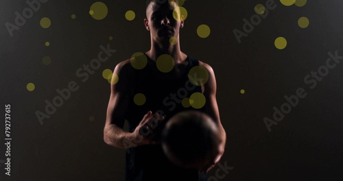 Image of caucasian basketball player throwing ball and spots of light on black background