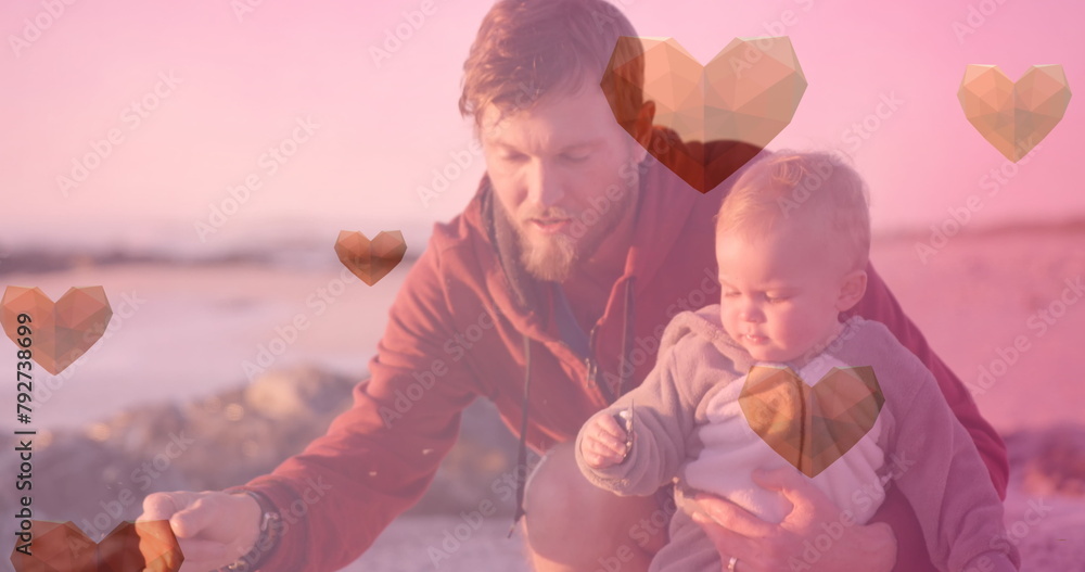Fototapeta premium Image of heart icons over caucasian father with child at beach