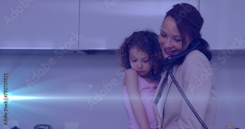 Image of glowing spots over happy caucasian mother with daughter taking on the phone