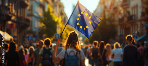 People holding a European flag in a city street at sunset.