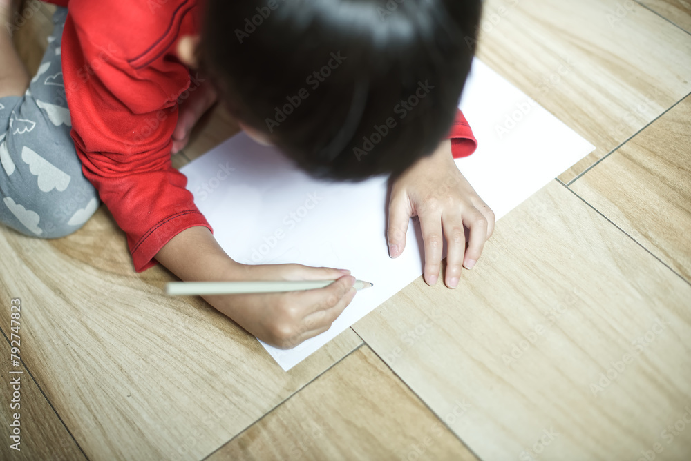 Little asian boy sitting on ground and drawing on paper Little asian boy sitting on ground and drawing on paper