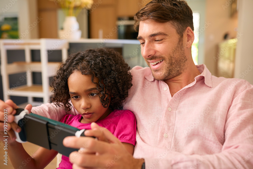 Multi Racial Family With Father And Daughter Playing On Handheld Gaming Device Together Multi Racial Family With Father And Daughter Playing On Handheld Gaming Device Together