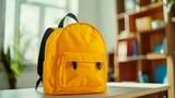 A yellow backpack stands on a desk against a blurred classroom background. School supplies. Back to school. Education concept