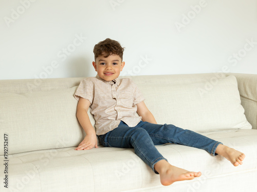 Adorable mixed race smiling five-year old boy sitting on couch relaxing, Quebec City, Quebec, Canada