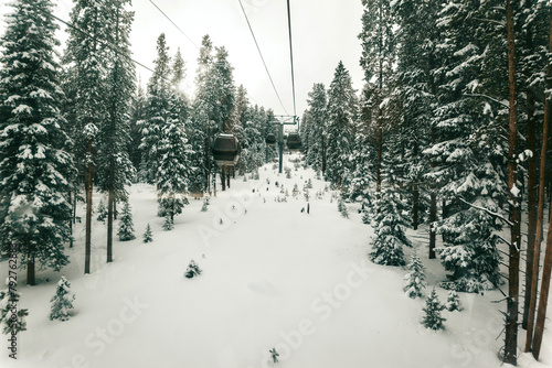 Ski gondolas ascend through a serene snowy forest.