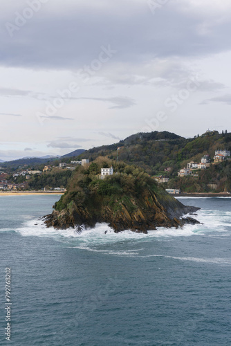 view of the coast on cloudy day with big waves and the island turtle in the middle photo