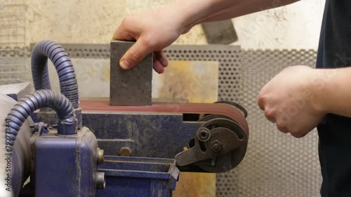 Factory Worker Polishing The Edges And Surface Of Metal Block With Linishing Machine - close up shot photo