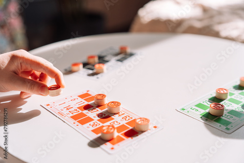 A woman's hand puts a keg on a number on a card from the lotto board game.