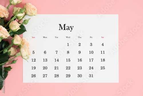 Flat lay of May 2024 paper desk calendar, top view. White beautiful roses on a pastel pink background.