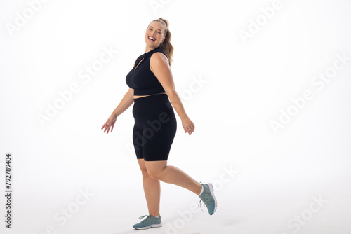 Caucasian young female plus size model on white background is laughing and walking, copy space