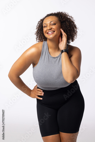 Biracial plus-size young female model laughs, touching her face; white background