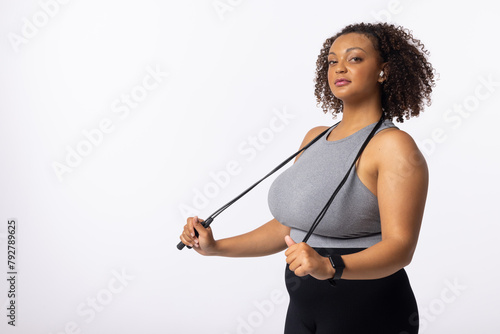 A biracial young female plus size model holds resistance bands on white background, copy space