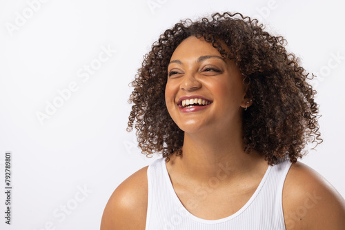 A biracial young female plus size model laughs on white background, copy space