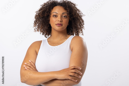 Biracial young plus size model stands with arms crossed on white background, copy space