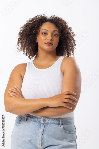 Biracial plus size model stands with arms crossed on white background