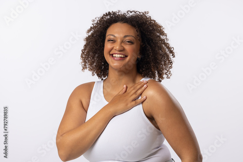 A biracial plus size model with curly brown hair laughs on white background, copy space