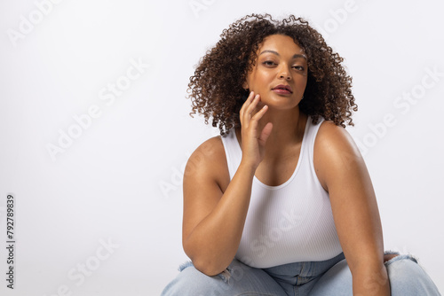 A biracial young female plus size model sits on white background, copy space © WavebreakMediaMicro
