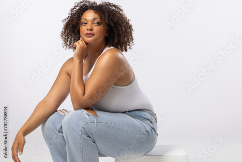 Biracial plus size model sits on white background, copy space
