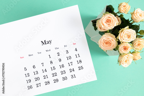 Flat lay of May 2024 paper desk calendar, top view. White beautiful roses on a pastel mint background.