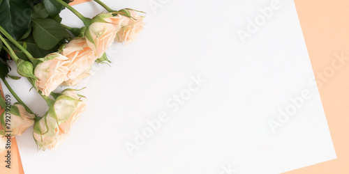Blank white paper, bouquet of light beautiful cream roses on a pastel beige background. Festive flower composition. Top view, flat lay.