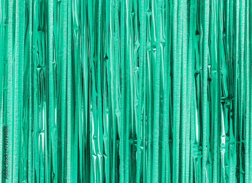 Green turquoise foil strip background. Curtain hanging on wall. Festive, Christmas, New Year or anniversary party concept. Decorative wallpaper