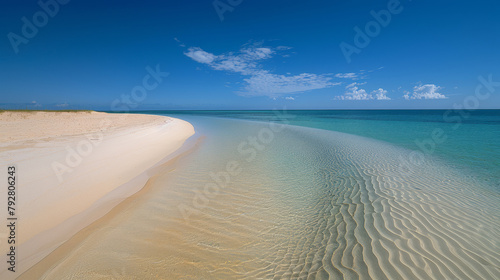 A beach with a clear blue ocean and a sandy shore. The water is calm and the sky is clear