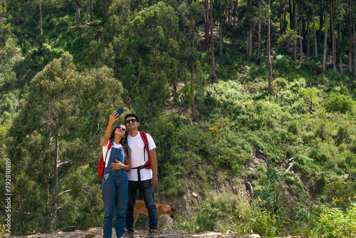 Two Travelers, a Man and a Woman, Taking a Selfie an a Mountain, Surrounded by Trees and Nature