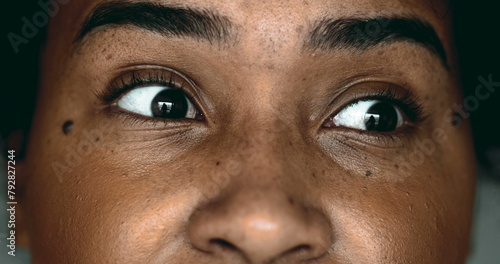 One Horrified Young Black Woman in Macro Close-Up, Eyes Wide Open in Shock looking sideways, Expressing Fear and Paranoia photo