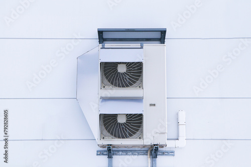 Structure big air conditioner compressor source heat pumps on wall outdoor have cover on side. Attaches to side of building for cooling industrial plant. Cooling pump technology for home or office.