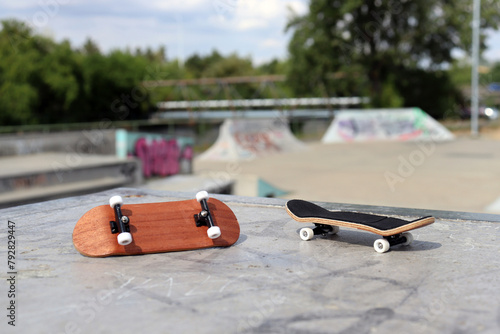 Blank wooden fingerboards at ramp in skatepark in the background. Mini skateboard, small skateboard deck