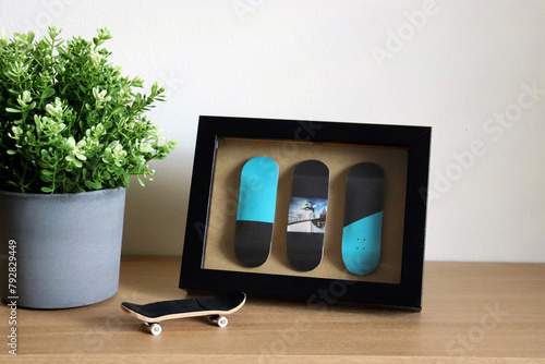 Wooden fingerboard on the table with fingerboard in the frame picture as a modern decor with flower. Mini skateboard, small skateboard deck