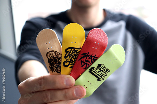 Male hand holding blank wooden fingerboard, close up. Mini skateboard, small skateboard deck