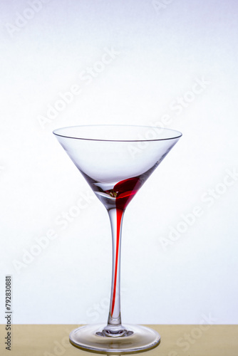 Martini glass on a beautiful long stem with a red accent on a light background