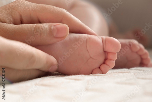 Tiny Babies Feet in Mother Hands. Close up of Small Bare Foot of Infant Sleeping on Soft Bed. Mom Stroking Cute Newborn Baby Toes. Childhood, Maternity, Health. Sleep Newborn Child Concept. Skin care
