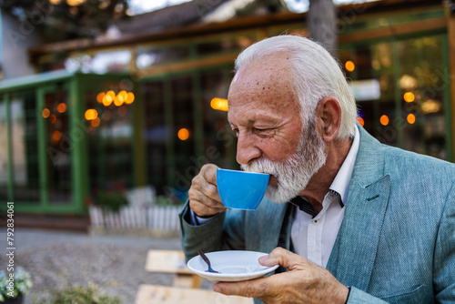 Thoughtful mature man drinking coffee in a cafe and looking away. Portrait of a bearded senior man drinking coffee in a cafe.