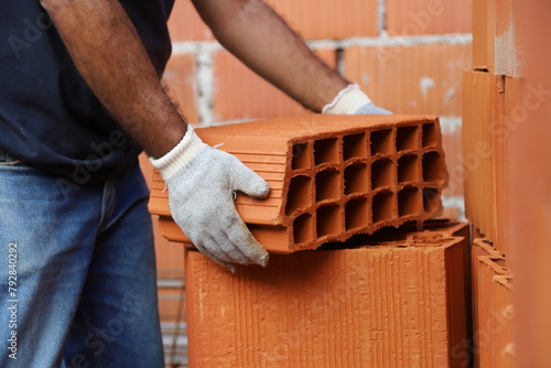Construction worker lifting a brick. Builder working on construction site. Professional bricklayer working on house construction. Concept of architecture, construction, industry, construction worker. © Acento Creativo