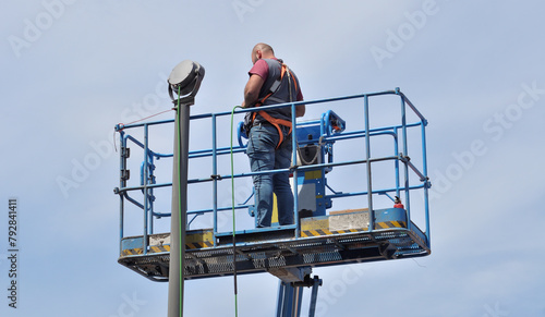 Male person working on an elevator platform, electrical lighting connection