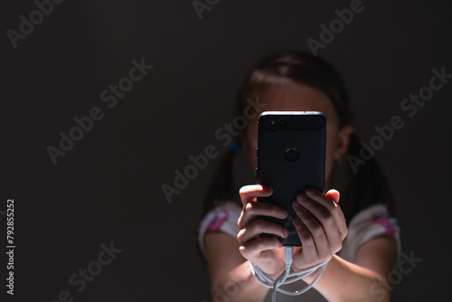 Young girl at night communicates on Internet. Child gadget addiction and insomnia. Anxiety and sleep deprivation as the side effects of internet addiction in children and young people. Copy space.