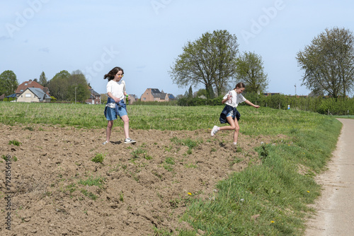 Two teenage girls run across a freshly plowed field for planting crops