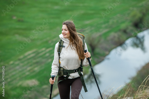 Successful hiker hiking on seaside mountain peak. Young beautiful female backpacker traveling alone. Attractive girl traveler during holiday vacation trip.