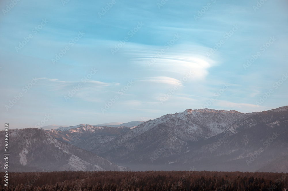 Cold snowy mountain landscape at sunset. Lenticular clouds.