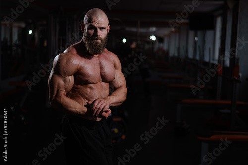 Caucasian bald man posing in the gym.