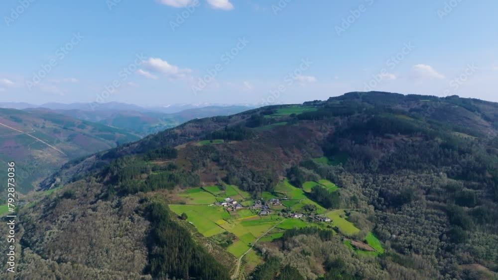 Aerial view of a mountainside village surrounded by dense green woods in Fonsagrada, Lugo, Spain Aerial view of a mountainside village surrounded by dense green woods in Fonsagrada, Lugo, Spain