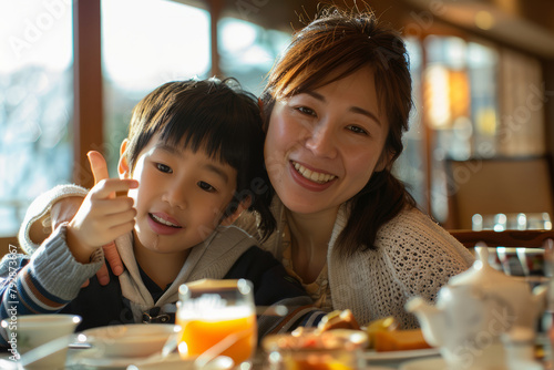 A content Japanese mother and son snap a selfie during family breakfast in the restaurant  cherishing their time together with genuine smiles and a peaceful ambiance.