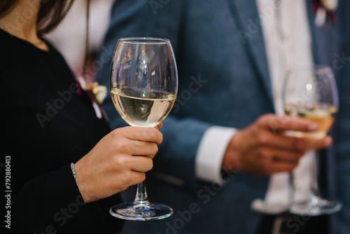 Tasting white wine. Couple drinking wine closeup. Beautiful girl and man holding glass of wine indoors. People hands hold glass of champagne. Friends and summer concept.