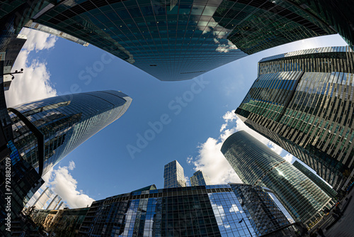 Looking up at tall, glass skyscrapers of Moscow City financial district with a fisheye lens, with blue sky and clouds.