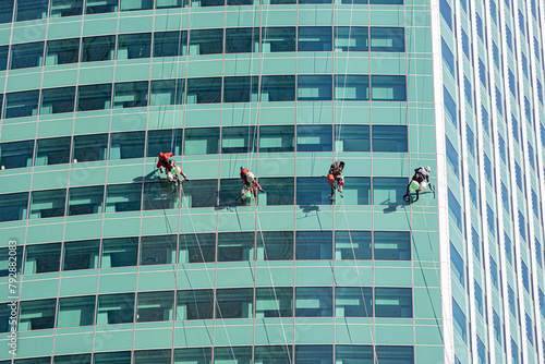 Window cleaners on a tall glass skyscraper in Moscow City financial district; men cleaning windows on a high rise glass office block in Russia.