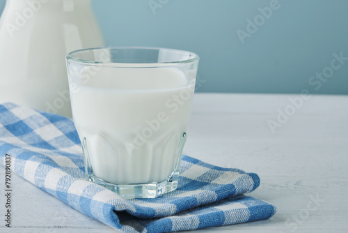 Milk in jug and glass on wooden table and blue background. Concept of farm dairy products, milk day. Kitchen or supermarket mock up for design. Copy space. © kasia2003